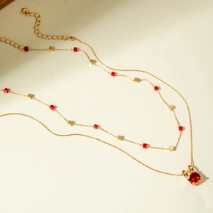 Détail d'un collier doré double rang avec pendentif rubis et perles cubiques