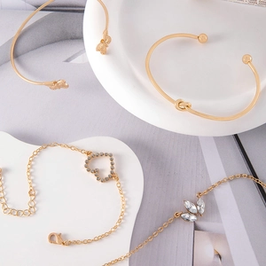 Four-piece gold bracelet set featuring heart, leaf, and butterfly designs with crystals