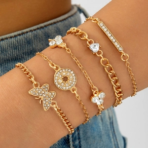 Five-piece gold bracelet set with butterfly and heart charms for women on denim background