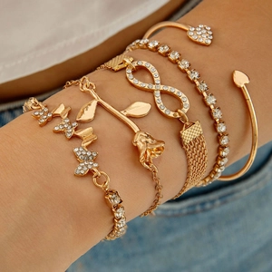 Close-up of gold layered bracelet set featuring butterfly, rose, and heart charms with crystals