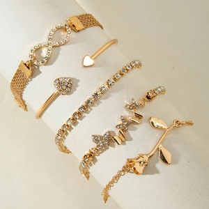 Detail of five-piece gold bracelet set with infinity symbol, heart, and butterfly charms