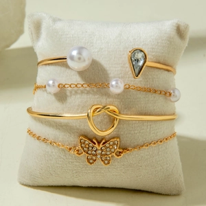 Detail of four-piece gold bracelet set with butterfly pendant and pearl embellishments
