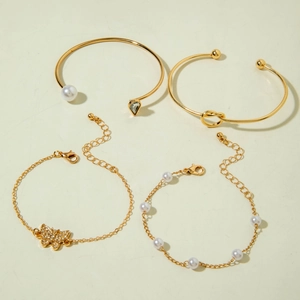 Detail of four-piece gold bracelet set with butterfly pendant, pearls, and green crystals