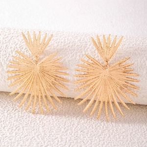 Macro shot of gold sunburst layered earrings with brushed texture on white surface