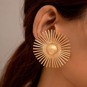 Macro view of gold sunburst flower earrings showing the radiant matte finish texture