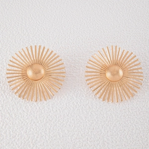 Detailed close-up of golden sunburst stud earrings with matte center on white background
