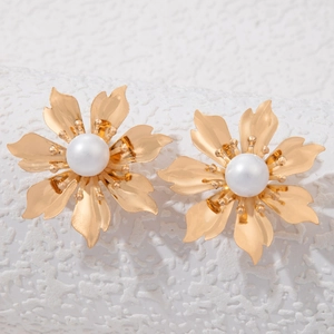 Detail of gold floral stud earrings with polished petals and central white pearls
