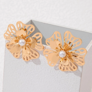 Detail of gold hollow flower earrings with white pearl center and intricate wire design