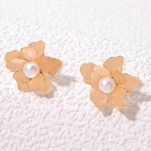 Macro view of gold petal earrings with multi-layer 3D floral design and white center pearls