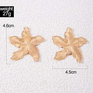 Detailed view of gold star earrings with leaf-like texture and 4.6cm size dimensions