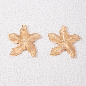 Detail of gold flower earrings featuring textured five-petal petals and vintage metallic finish
