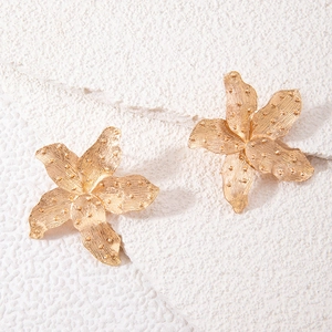 Detailed close-up of golden alloy flower earrings with matte finish and textured petals