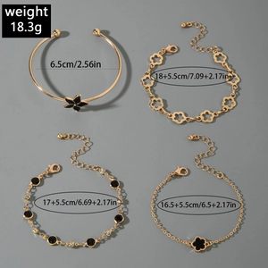 Détail d'un ensemble de quatre bracelets dorés avec breloques fleurs noires et papillons
