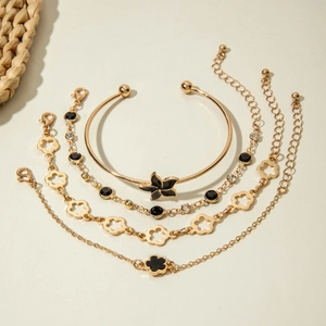 Détail du set de quatre bracelets dorés avec fleurs en émail noir et strass brillants