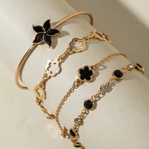 Détail d'un ensemble de quatre bracelets dorés avec fleurs noires et strass brillants