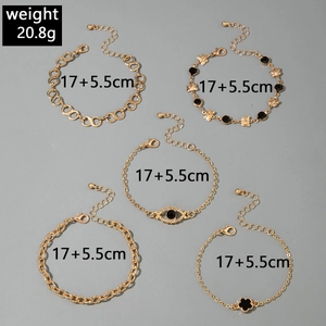 Détails de cinq bracelets dorés avec breloques papillon, œil grec et fleur élégante