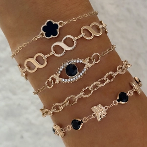 Détail d'un ensemble de cinq bracelets vintage avec trèfle et œil maléfique portés au poignet