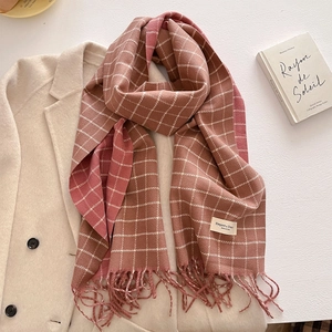 Detail of pink plaid scarf with elegant label and fringes on a beige coat