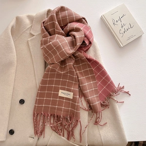 Detail of pink plaid scarf with tassels on a beige wool coat with a classic brand label