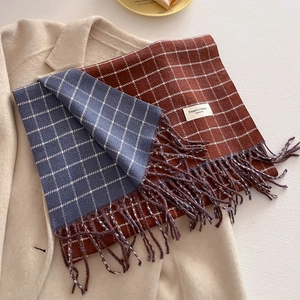Detail of knit plaid scarf showing dual-sided colors in caramel and blue with fringe