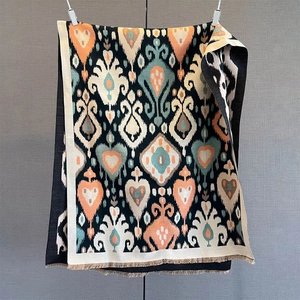 Detail of bohemian paisley shawl showing orange ikat pattern and fine fringe edges