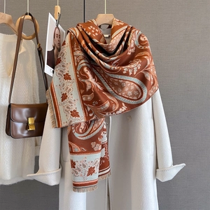 Detail of paisley pattern cashmere-feel scarf draped on a coat with fringe texture