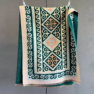 Detail of green paisley cashmere-feel scarf with folk patterns and fringe texture