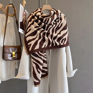 Close-up of zebra pattern knit scarf with fringe tassels on a white winter coat