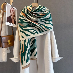 Detail of irregular striped cashmere-like scarf with fringe on white coat