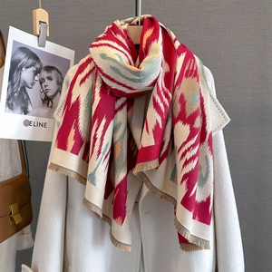 Detail of cashmere feel scarf with paisley patterns and soft tassels on white coat