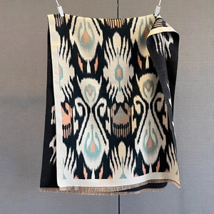 Close-up of ikat pattern knit shawl featuring geometric motifs and fringe tassels