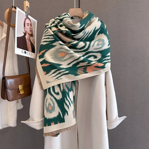 Close-up of thick geometric knit scarf with fringe detail on beige coat
