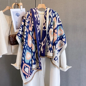 Close-up of bohemian heart print scarf with tassels over a wool coat on a hanger