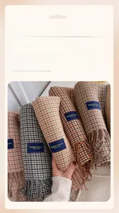 Close-up of soft plaid scarf featuring fringed edges and an elegant blue fabric label