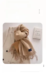 Detail of checkered houndstooth scarf with tassels on beige coat and book background