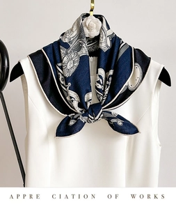 Détail d'un foulard en soie à imprimé floral bleu marine et décoration de camélia