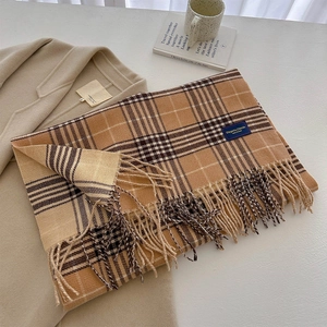 Close-up of yellow plaid knit scarf with long tassels paired with a beige coat