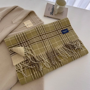 Detailed texture of a green plaid tassel scarf paired with an apricot wool coat