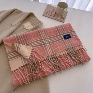 Detail of pink and beige plaid scarf with thick tassels on a warm wool coat