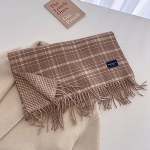 Detail of plaid tassel scarf with brown and beige knit texture on woolen coat
