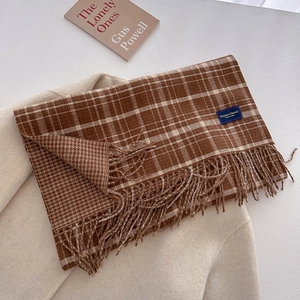 Detail of soft thick knit tassel scarf with brown beige plaid pattern and brand label