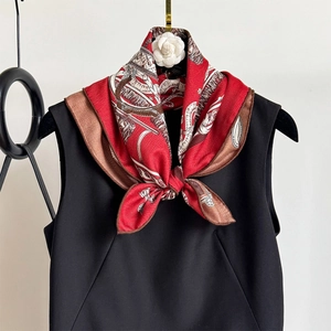 Gros plan d'un foulard en soie rouge avec motifs équestres sur un vêtement noir chic