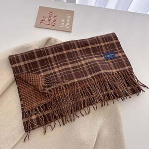 Detail of coffee brown plaid scarf with fringe on minimalist beige wool coat background