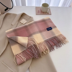 Close-up of thick checkered scarf with tassel detail and label on beige coat