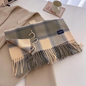Detail of plaid scarf with thick fringe on khaki coat with magazine and coffee cup