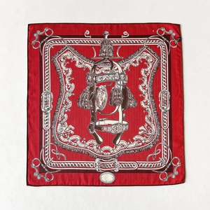 Gros plan détaillé du foulard en soie rouge foncé avec motifs équestres et pompons