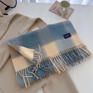 Close-up of classic plaid scarf with blue and beige fringe and brand label details