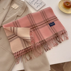 Detail of pink and beige plaid scarf with tassels and an elegant fabric label