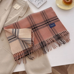 Detail of checkered cashmere-like scarf with fringe and elegant woven label on fabric