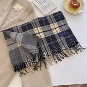 Detail of plaid scarf with tassels in navy blue and beige on a camel wool coat